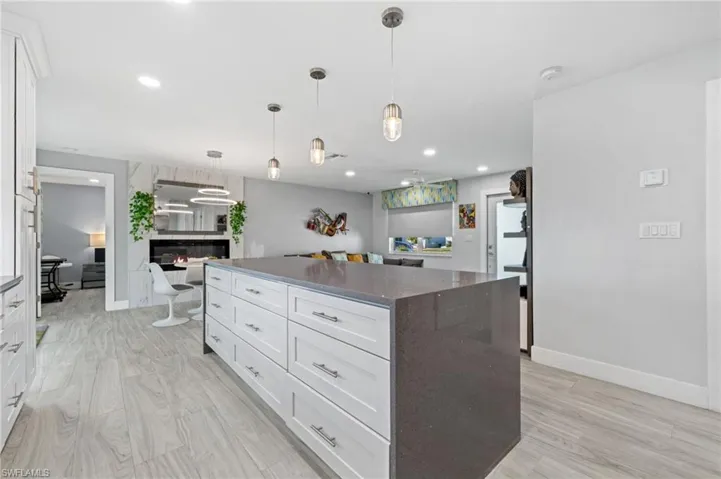 Kitchen featuring a center island, white cabinetry, light wood finished floors, and pendant lighting