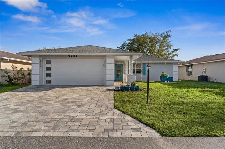 View of front of home featuring a front yard, an attached garage, decorative driveway, and stucco siding