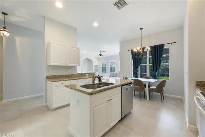 Kitchen featuring decorative light fixtures, a ceiling fan, a chandelier, white cabinets, and light stone countertops