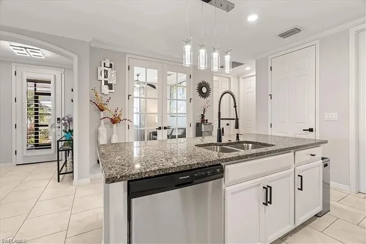 Kitchen featuring french doors, stainless steel dishwasher, light tile patterned floors, pendant lighting, and white cabinets
