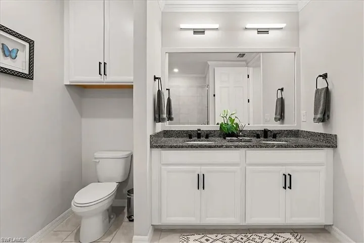 Bathroom with double vanity, crown molding, and light tile patterned floors