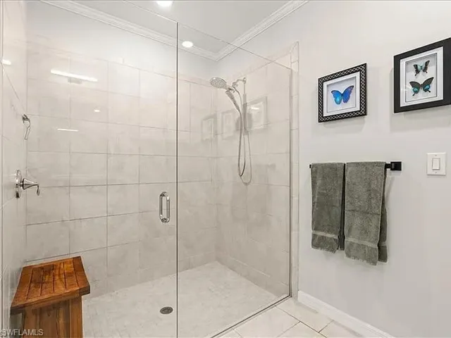 Bathroom with a shower stall, tile patterned floors, and ornamental molding