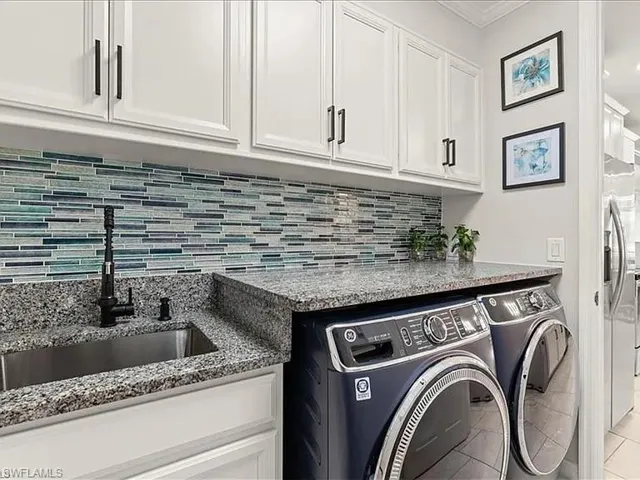 Laundry area featuring washing machine and clothes dryer, ornamental molding, and tile patterned floors