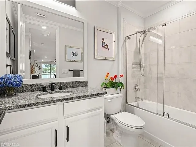 Full bath with bath / shower combo with glass door, vanity, and crown molding