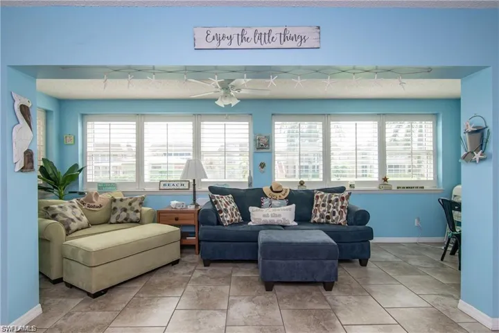 Expansive room framed by a wide archway, featuring tile flooring and a ceiling fan
