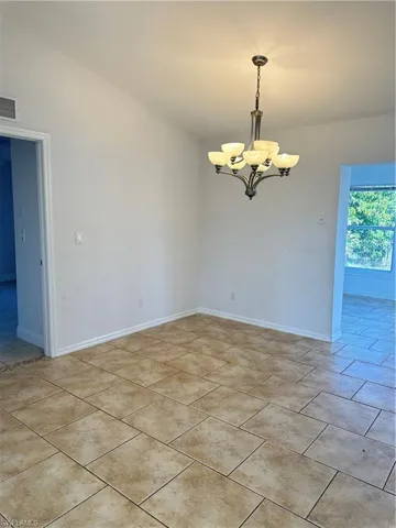 Unfurnished room with a chandelier and baseboards