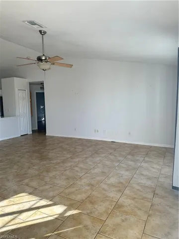 Unfurnished room with vaulted ceiling, a ceiling fan, and light tile patterned flooring