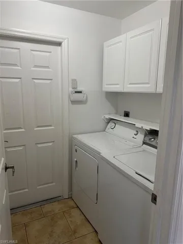 Laundry room with cabinet space, light tile patterned floors, and washing machine and clothes dryer