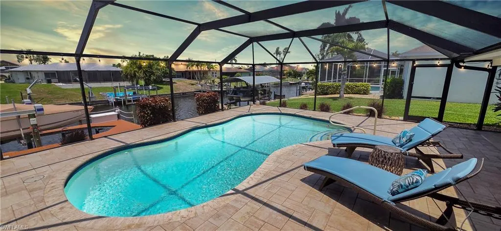 Screened pool enclosure featuring a freeform swimming pool, paver deck, and direct water access with a boat dock