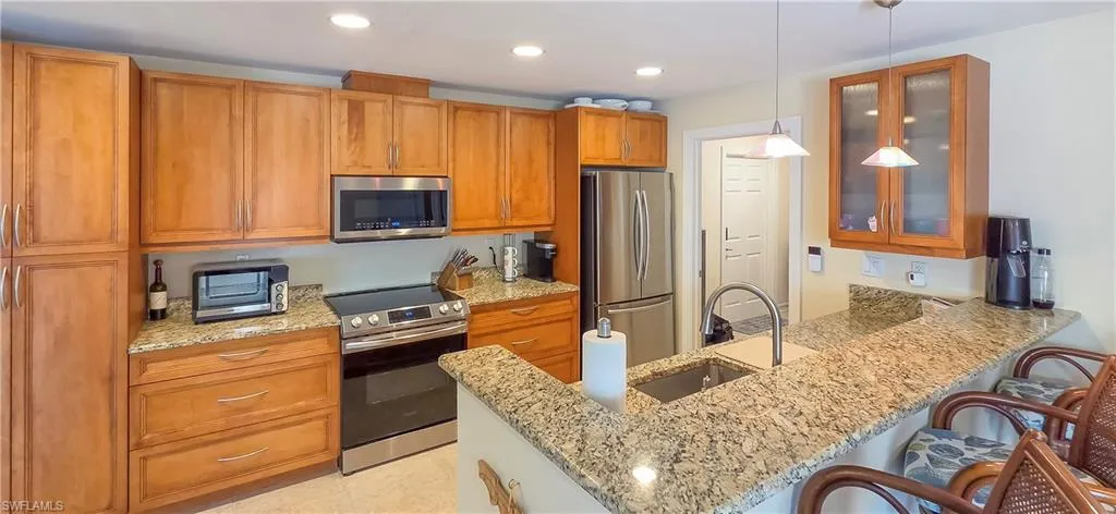 Kitchen featuring extensive cabinetry in a wood finish, granite countertops, and stainless steel appliances including a range and microwave