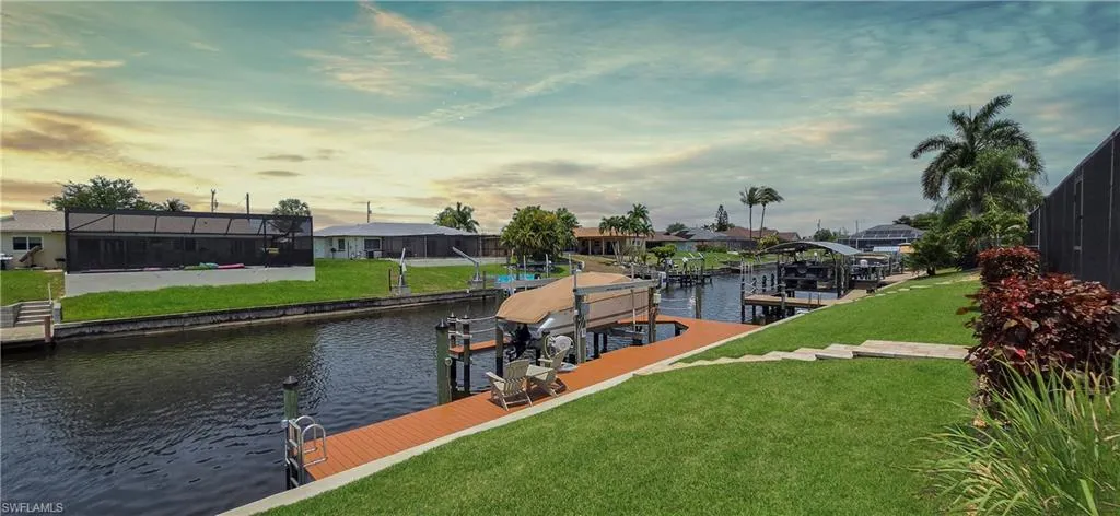 Waterfront property featuring a private boat dock with lift, direct canal access, terraced lawn, and mature landscaping