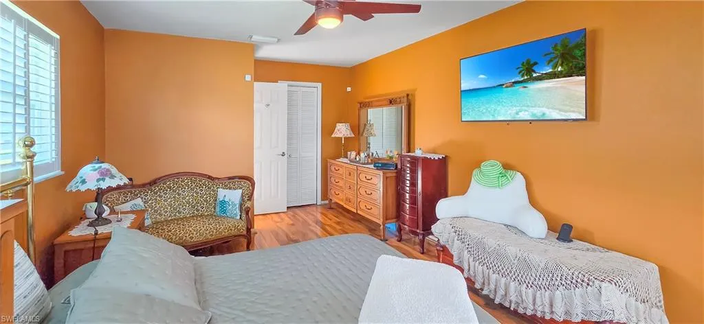 Interior room featuring wood-finish flooring, a ceiling fan, and white plantation shutters