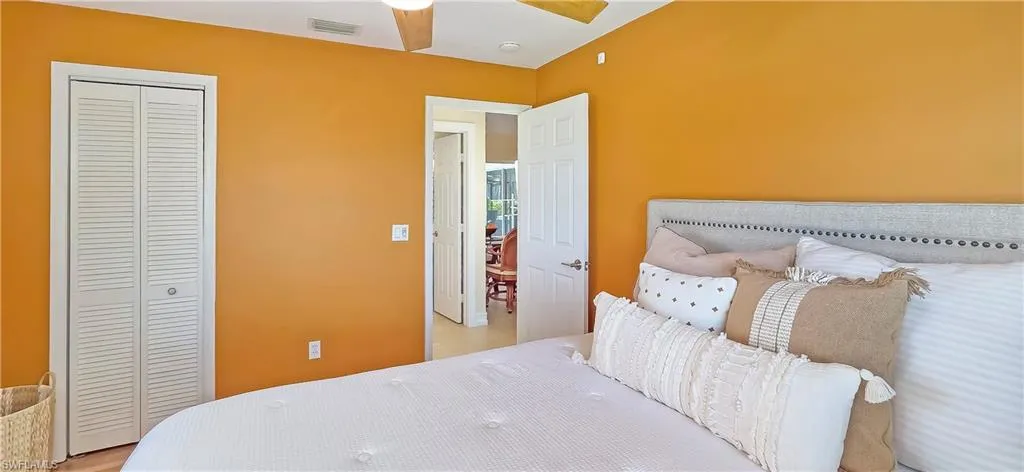 Interior room with warm-toned walls, featuring a ceiling fan, a louvered bi-fold closet, and a doorway opening to another interior space
