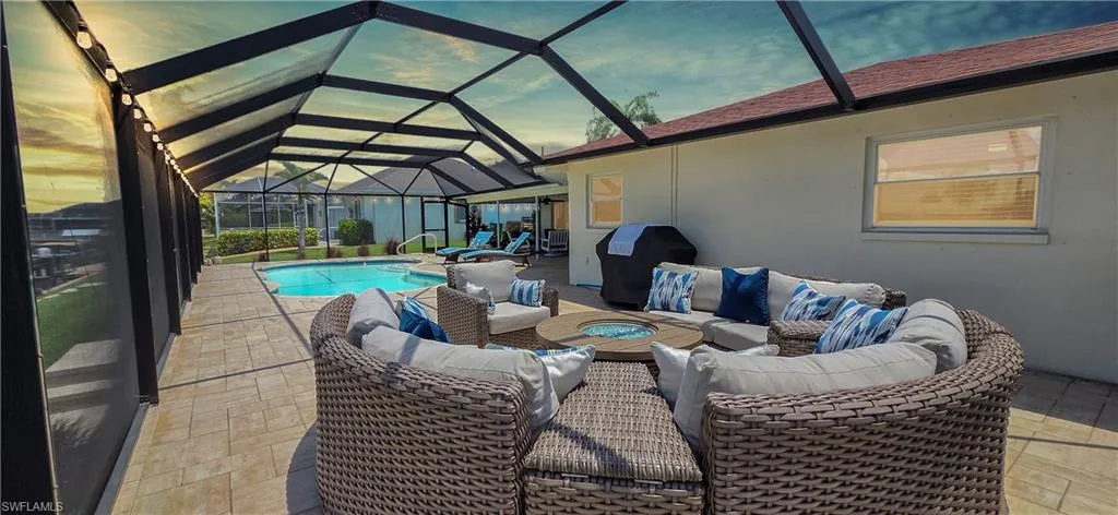 Screened lanai featuring a swimming pool, textured patio flooring, and a built-in fire pit