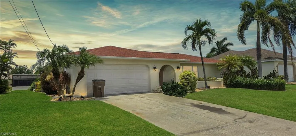 Ranch-style residence featuring a prominent two-car garage, concrete driveway, and a red tile roof