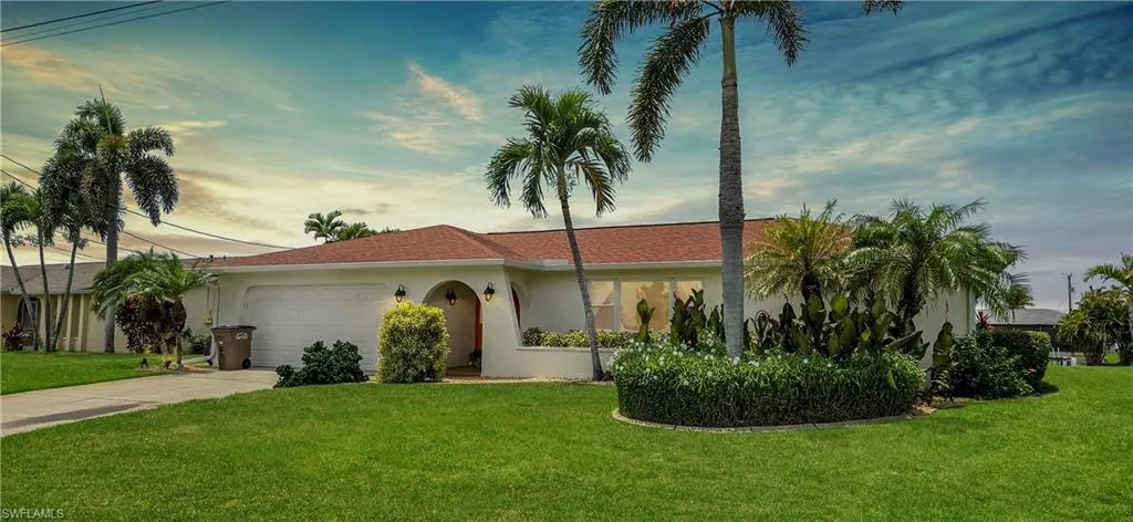 Single-story stucco residence featuring an orange tile roof and a prominent curved front entrance with arched alcoves