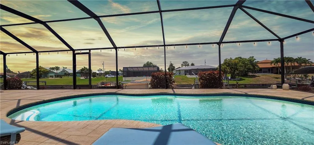 Screened-in outdoor pool featuring a paved deck and integrated lighting
