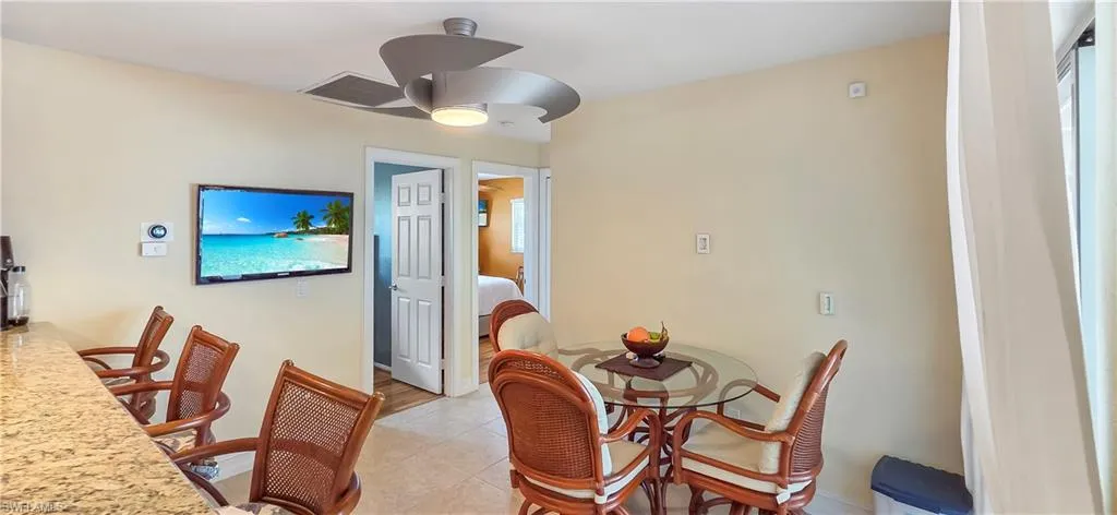 Open-concept living area featuring a granite-top breakfast bar, tile flooring, and a modern ceiling fan
