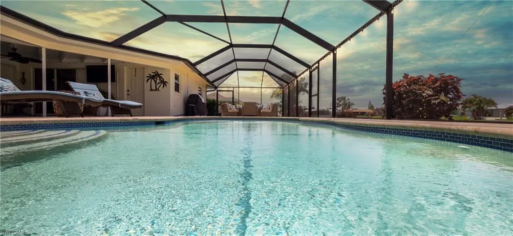 Screened lanai featuring a swimming pool with tiled coping, a covered patio area, and an outdoor ceiling fan