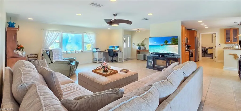Open-concept living area with neutral tile flooring, recessed lighting, and a ceiling fan