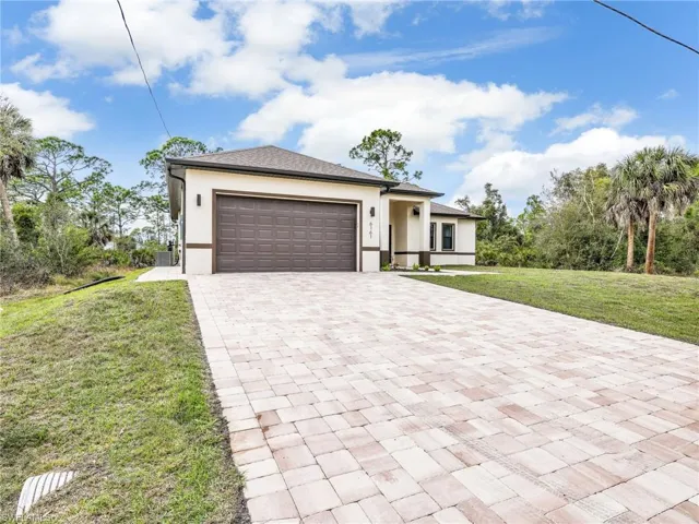 Prairie-style house featuring a front yard, stucco siding, an attached garage, and decorative driveway