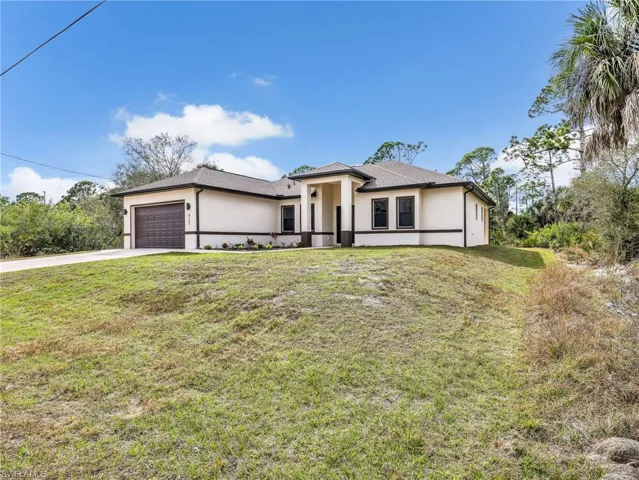 Prairie-style house with an attached garage, a front yard, stucco siding, and concrete driveway