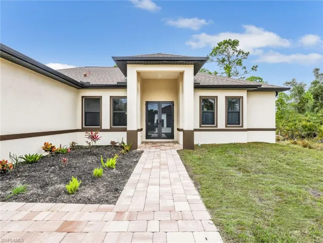 Property entrance featuring stucco siding, roof with shingles, french doors, and a lawn
