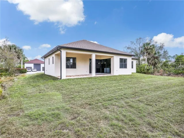 Rear view of house with a yard, stucco siding, and a patio area