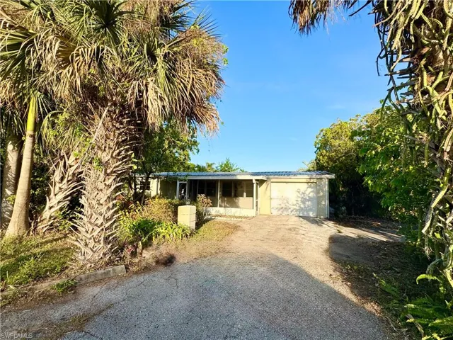 Ranch-style house featuring metal roof, driveway, and an attached garage