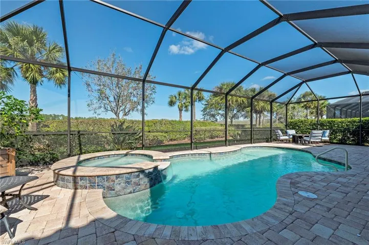 View of pool featuring glass enclosure, an in ground hot tub, and a patio