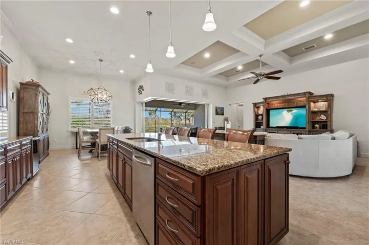 Kitchen featuring light stone countertops, a center island, pendant lighting, and ceiling fan with notable chandelier
