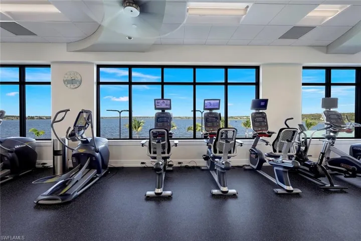Exercise room with ceiling fan, a drop ceiling, and a water view