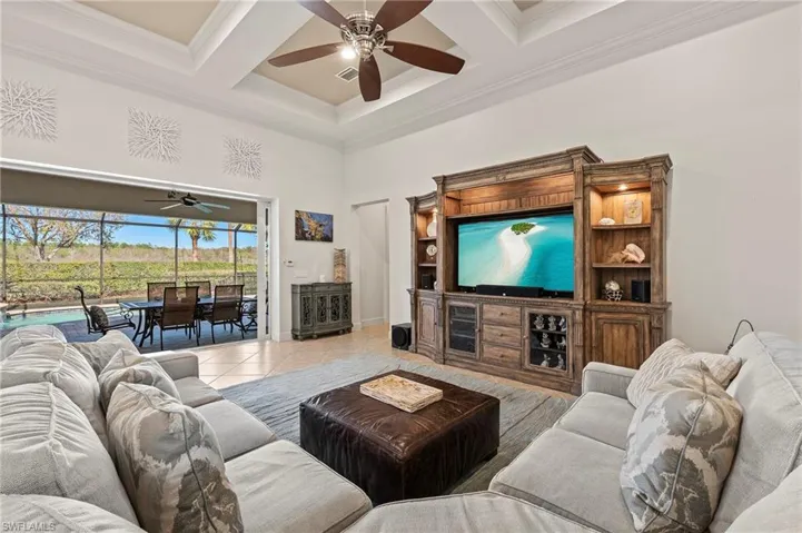 Living room with tile patterned floors, beam ceiling, crown molding, and coffered ceiling