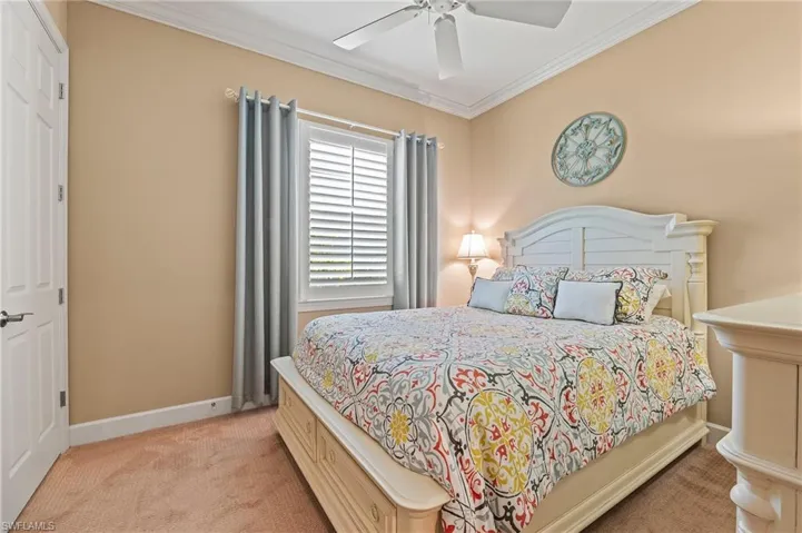 Bedroom featuring ceiling fan, light colored carpet, and ornamental molding