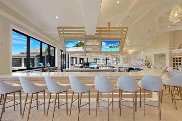 Bar featuring vaulted ceiling with beams and light stone countertops