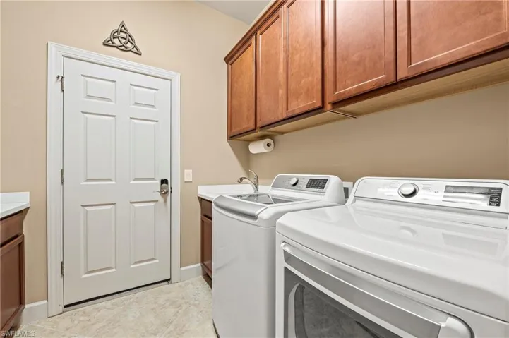 Washroom featuring cabinets, light tile patterned floors, independent washer and dryer, and sink