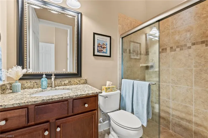 Bathroom with a shower with door, vanity, and toilet
