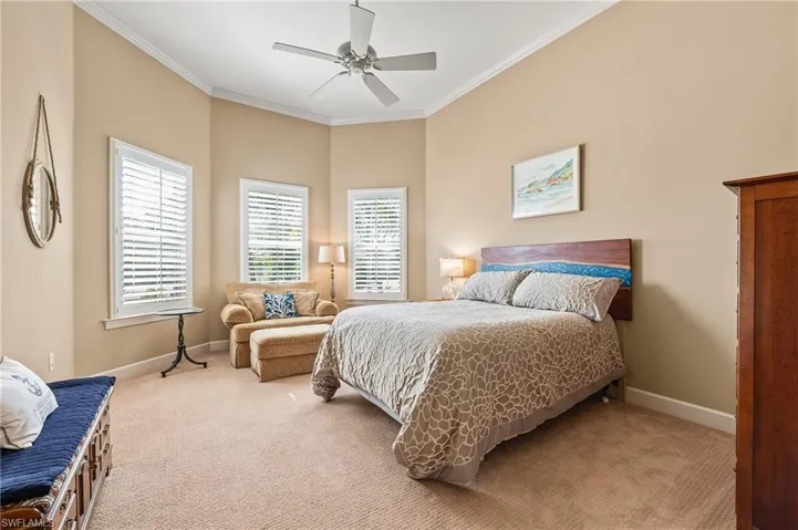 Bedroom with carpet floors, ceiling fan, and crown molding