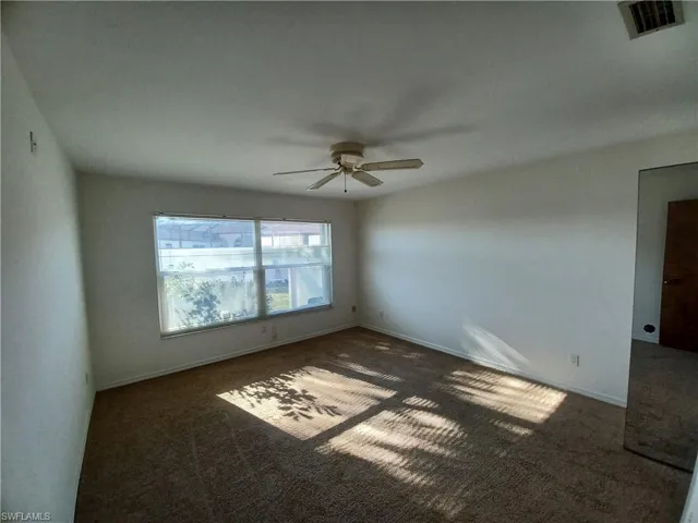 Unfurnished room with dark carpet and ceiling fan