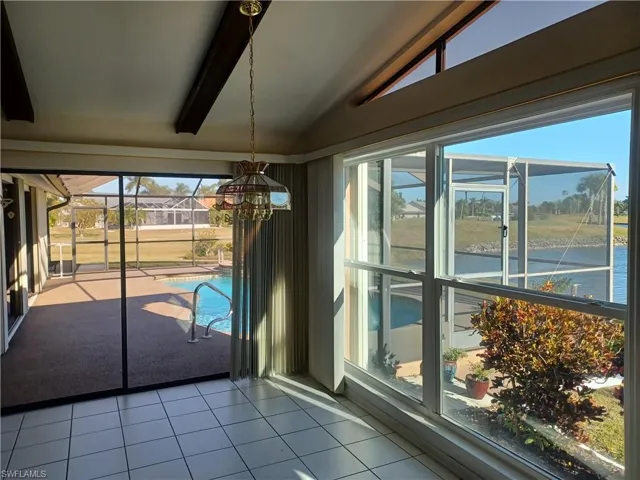 Unfurnished dining area with tile patterned flooring, vaulted ceiling with beams, and a water view
