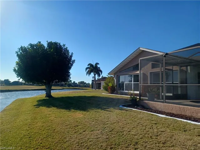 View of green lawn with a lanai, a sunroom, and a water view
