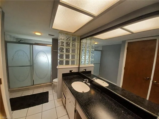 Bathroom with vanity, light tile patterned flooring, and an enclosed shower
