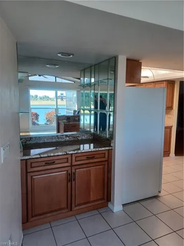 Kitchen featuring wood finish cabinetry, paneled refrigerator, dark stone countertops, and light tile patterned floors