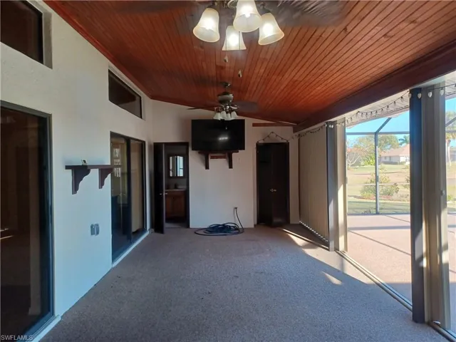 Unfurnished sunroom with a ceiling fan, a patio, and vaulted ceiling