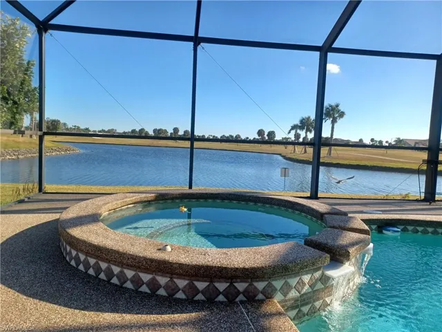 Relaxing pool / spa with a sunroom, a water view, and glass enclosure