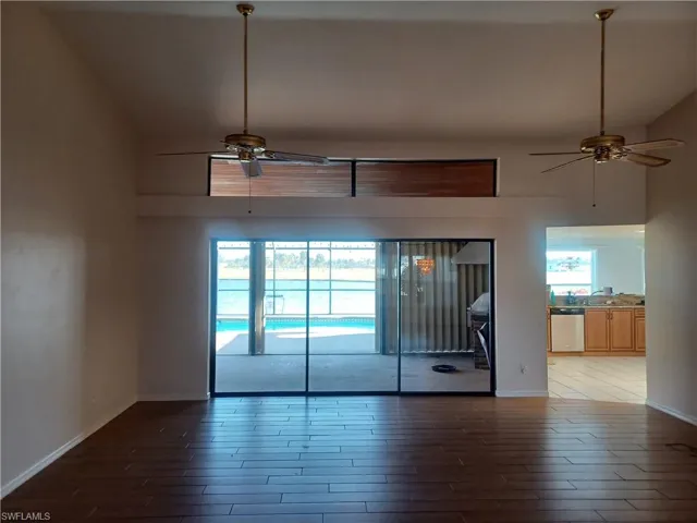 Unfurnished room featuring a ceiling fan, lofted ceiling, and dark wood-style floors