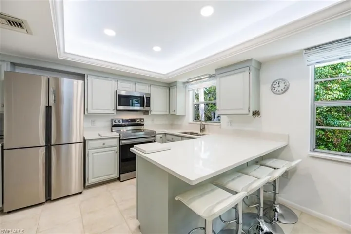 Kitchen with stainless steel appliances, a kitchen breakfast bar, a peninsula, and light countertops