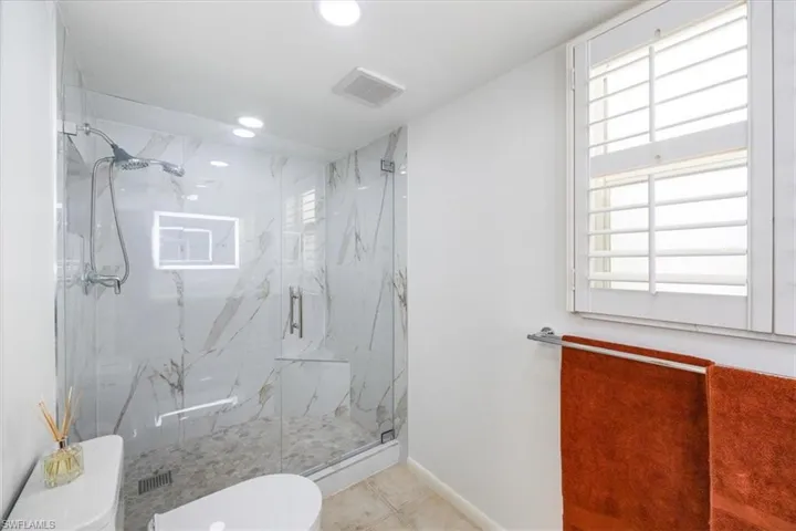 Bathroom with baseboards, visible vents, a marble finish shower, recessed lighting, and toilet