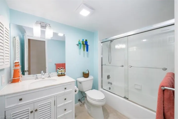 Full bathroom featuring vanity, tile patterned floors, toilet, and enclosed tub / shower combo