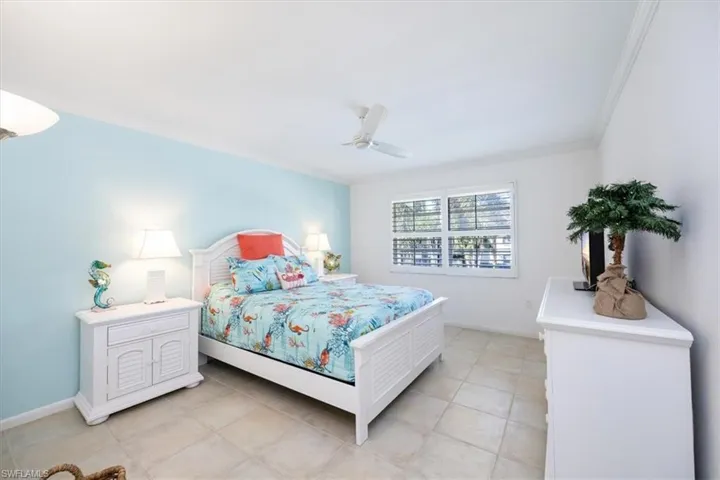 Bedroom featuring light tile patterned floors, a ceiling fan, crown molding, and baseboards
